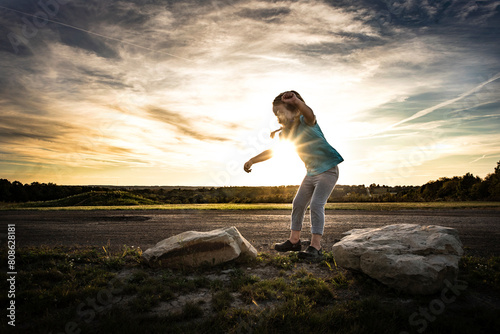 Little girl jumping across rocks in summer photo