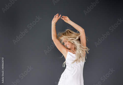 Joyful woman in white dress dancing on black background backgrou photo