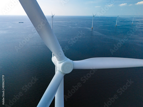 A mesmerizing view of windmill turbines generating clean energy in the vast expanse of the ocean, representing a harmonious blend of technology and nature © Fokke Baarssen
