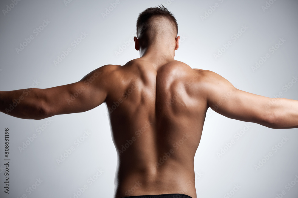 Back, flex and bodybuilder in studio with muscle, fitness and strong from training or exercise. Healthy, person and model stretching arms on background or mockup with wellness from workout in gym