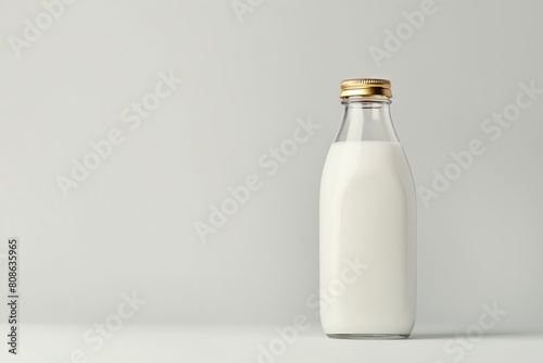 A single classic milk bottle filled with milk, isolated on a soft gray backdrop, with a clean and modern look photo