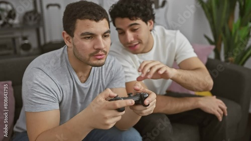 Two men focused on playing video games together in a cozy home interior indicating friendship and leisure activity. photo