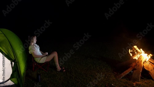 woman girl asiatic chatting typing on tablet while in front of bonfire with her camping tent photo