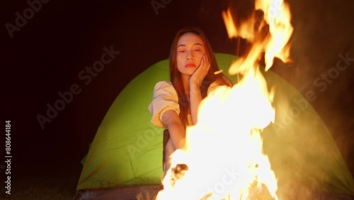 close up portrait of asiatic young woman camping at night in front of bonfire  photo