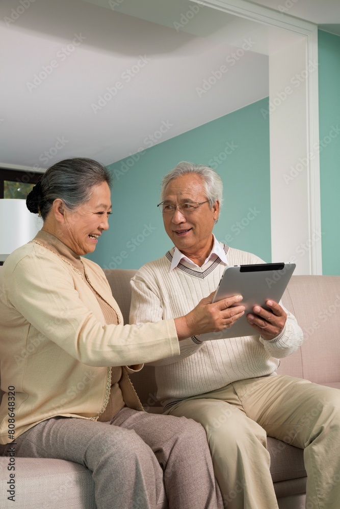 Elderly couples use tablet computers in the living room Elderly couples use tablet computers in the living room
