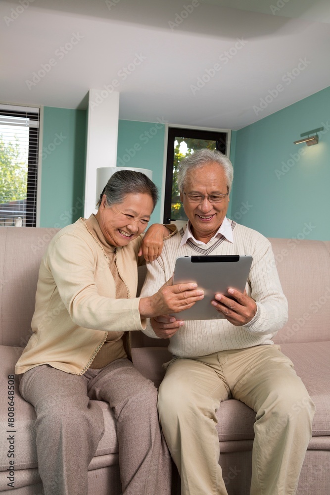 Elderly couples use tablet computers in the living room Elderly couples use tablet computers in the living room