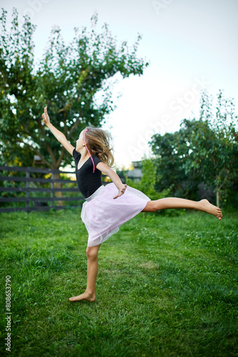 Young Girl Practicing Ballet Moves in a Green Garden at Dusk