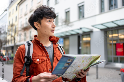 Asian young man backpacker traveler looking at map to find destination.  photo