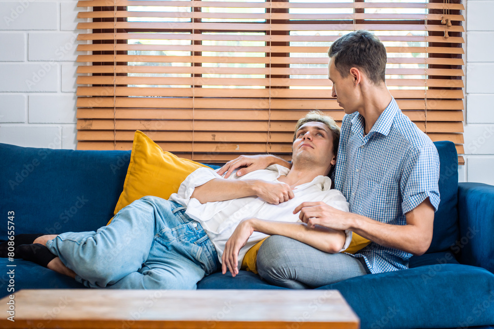Obraz na plátně Caucasian young male gay couple lying down on sofa together in house