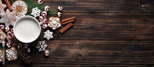Flat lay copy space image of a cup of hot chocolate adorned with marshmallows accompanied by gingerbread cookies gifts and tasteful Christmas ornaments all arranged on a rustic wooden background as s photo
