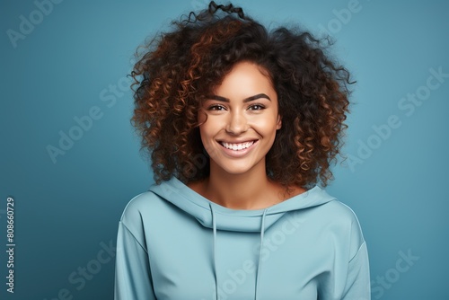 Smiling Caucasian girl with afro curls on a blue background. © Niko_Dali