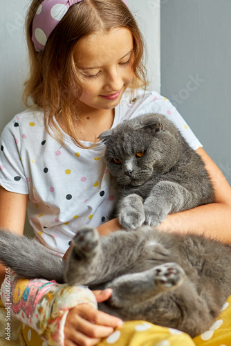 Teen girl with a broken arm orthopedic cast play with cat