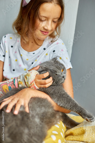 Teen girl with a broken arm orthopedic cast play with cat