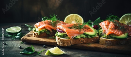 On a grey table there is a copy space image of open sandwiches topped with spinach and avocado salmon photo
