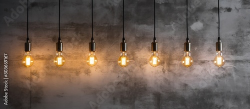The vintage style Edison retro lamp with incandescent bulbs is placed on a gray plaster wall background in a loft The image provides copy space photo