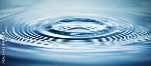 Water droplet creating ripples on the surface of a still body of water with ample empty space surrounding it for focus creating a captivating copy space image