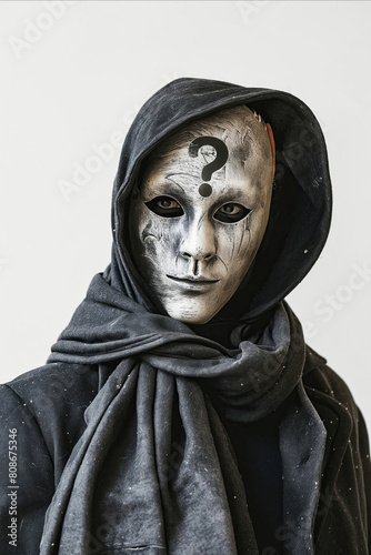A person is wearing a mask and a scarf. The mask has a question mark on it. The person is looking at the camera