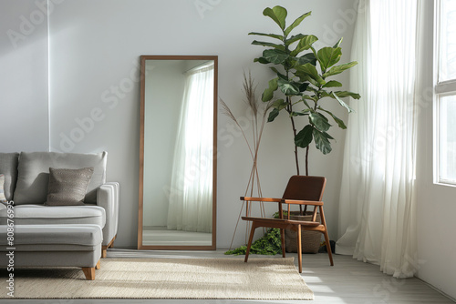 Stylish minimalist living room with a large floor mirror, cozy armchair, and green plant photo