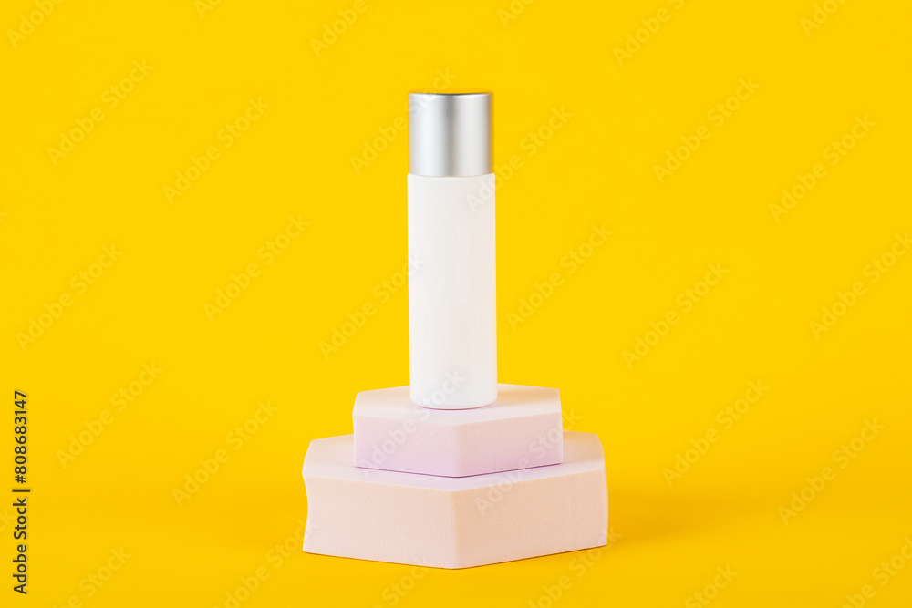 Plastic white tube for cream or lotion. Skin care or sunscreen cosmetic with stylish props on yellow background 