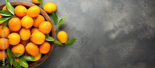 Top view of fresh organic kumquat fruits in a wooden bowl placed on a concrete background The vibrant healthy vegan food is emphasized by the cut up kumquats The image contains plenty of copy space photo