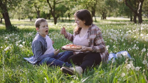 Offended child becomes nervous and freaks out when communicating with mother. Family sits on lawn in park during picnic with pizza. Difficulties of nature of adolescence, formation of nervous system. photo