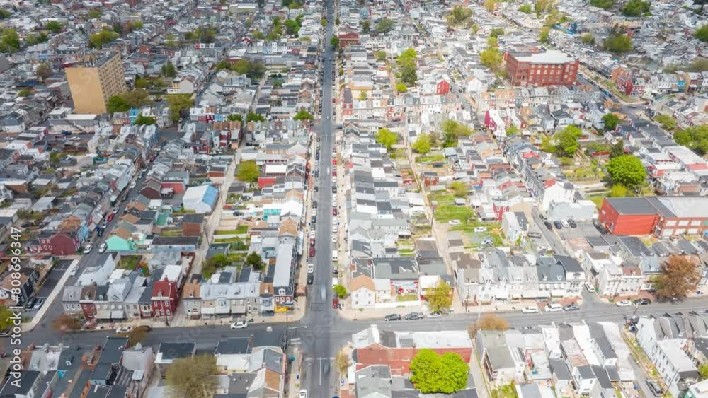Aerial hyperlapse view of a densely populated American city street lined with tightly packed houses and busy traffic. Top down view of row houses and cars traveling on city streets. Aerial hyperlapse view of a densely populated American city street lined with tightly packed houses and busy traffic. Top down view of row houses and cars traveling on city streets.