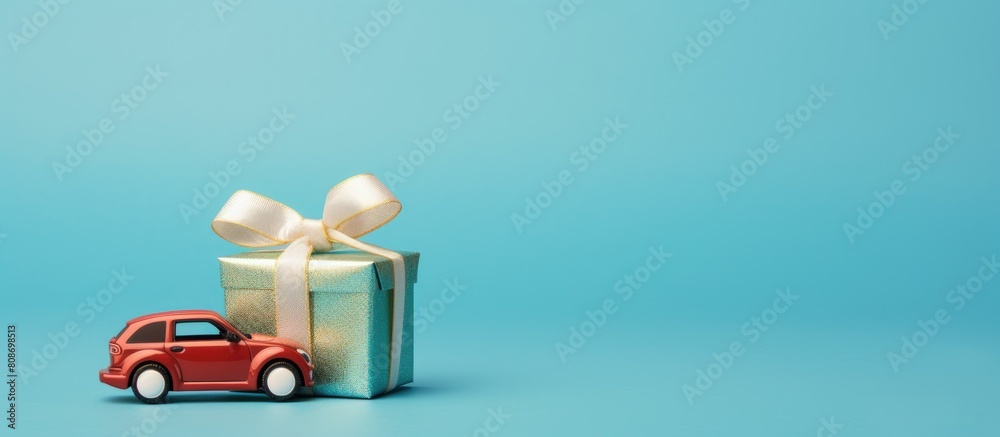 Fototapeta premium Toy car on blue background delivering Christmas or New Year gift Copy space image for holiday celebration and festive background Also suitable for Women s Day Mother s Day and Valentine s Day celebra