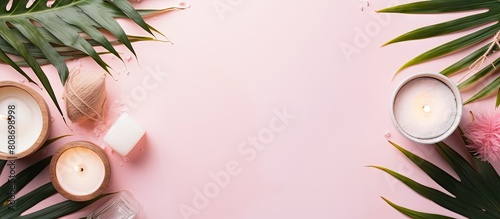 A top view of a spa setup on a pastel pink background featuring oils sea salt candles and tropical plants Ample copy space photo