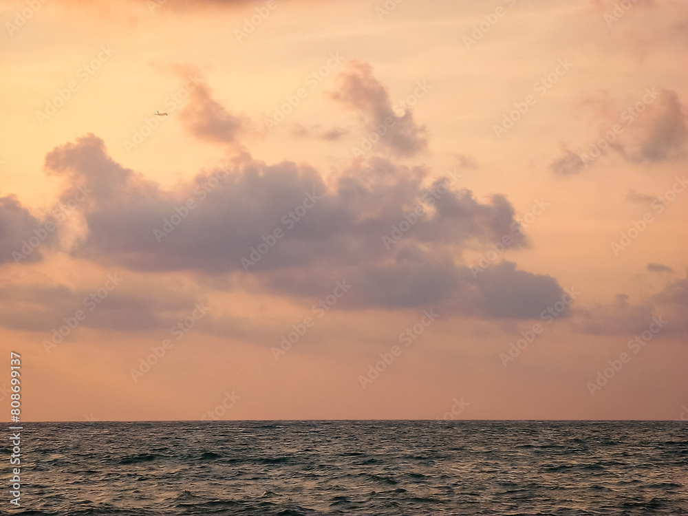 The sea and sky in evening. scenery of the sea that reflects the sunset view until it has an orange color with large clouds and airplane That flies at the end of the eye. Natural viewpoint vacations.