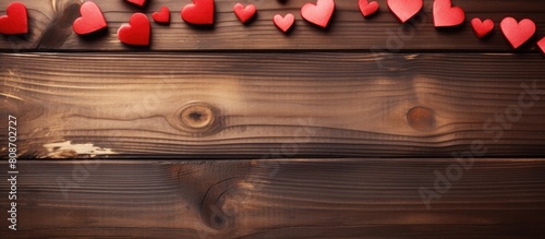 There is a copy space image featuring red hearts resting on a wooden brown background