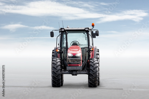 Front view of the red modern wheeled tractor isolated on bright background with sky