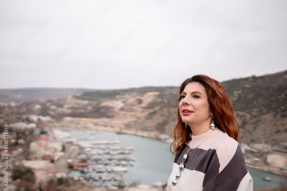 A woman is sitting on a rock overlooking a body of water. The scene is peaceful and serene, with the woman looking out over the water and taking in the view. A woman is sitting on a rock overlooking a body of water. The scene is peaceful and serene, with the woman looking out over the water and taking in the view.