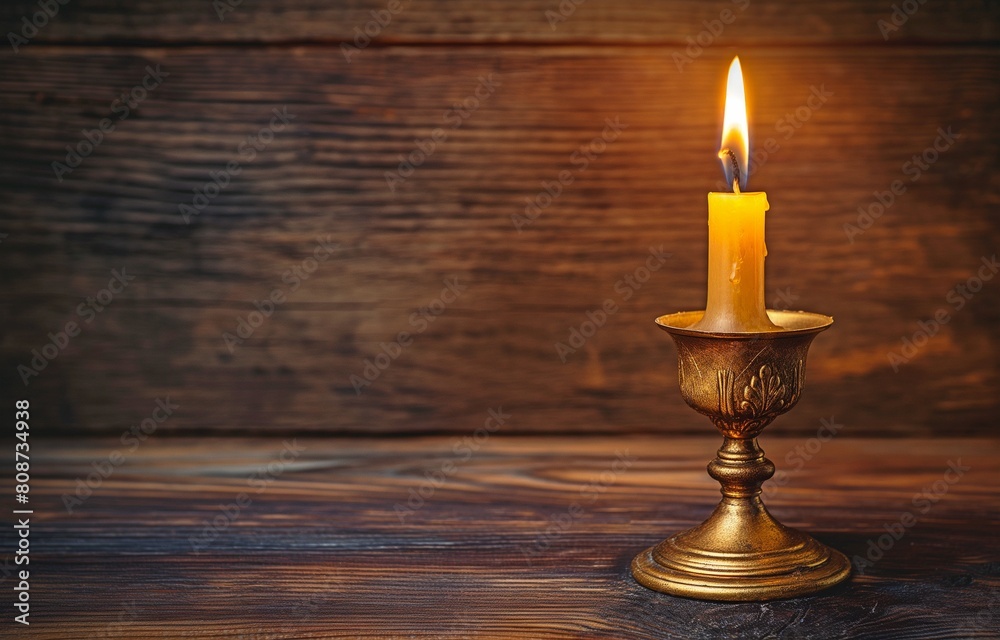 An antique brass candle stand set against a backdrop of dark timber with a burning candlestick An antique brass candle stand set against a backdrop of dark timber with a burning candlestick
