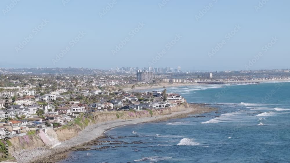 Aerial track back of San Diego, California shore and cliffside neighborhood with the skyline in the background on a sunny day. Aerial track back of San Diego, California shore and cliffside neighborhood with the skyline in the background on a sunny day.