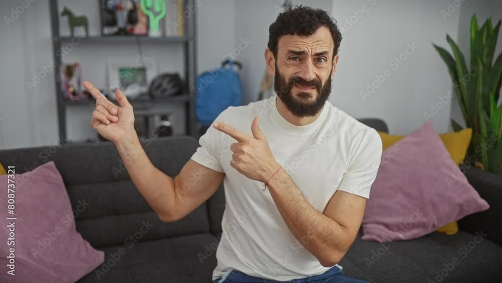 Worried middle-age man at home, nervously pointing aside, wearing a white t-shirt, expressing surprise and concern with both hands. Worried middle-age man at home, nervously pointing aside, wearing a white t-shirt, expressing surprise and concern with both hands.