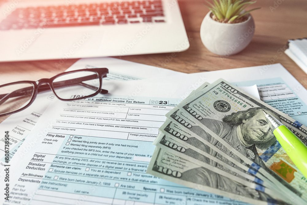 Φωτογραφία US 1040 tax form with dollar pen and laptop, april tax season