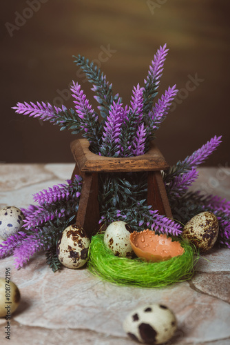 Quail eggs near the nest and lavender flowers on a stone background. Easter Postcard