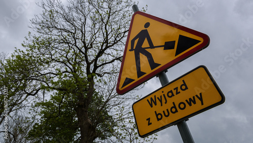 
ROADWORKS AREA - Worning sign on the trees background and a board with the inscription "exit from construction site"