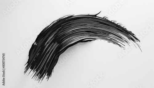 A textured image of a black mascara brush stroke against a white background, capturing the dynamic and artistic application of makeup