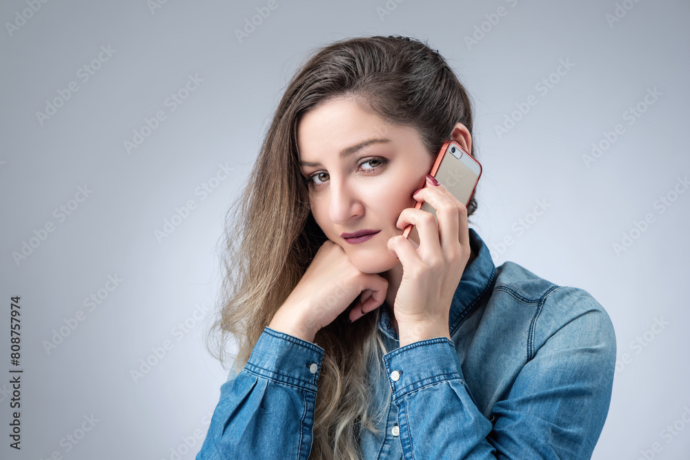 Portrait of a sweet sad young girl talking on a smartphone on a gray background Portrait of a sweet sad young girl talking on a smartphone on a gray background