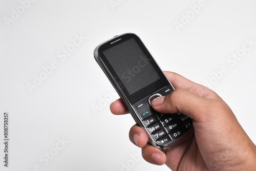 Hand holding Old Mobile Phone isolated on white background. Old cellular mobile phone