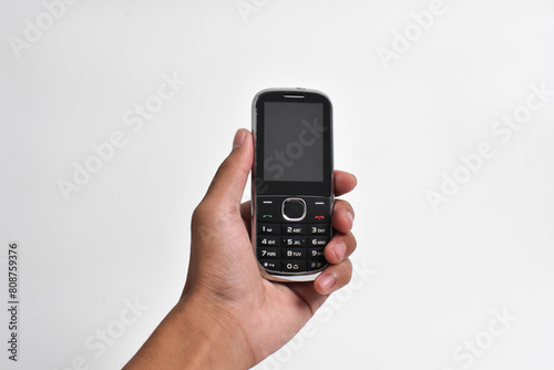 Hand holding Old Mobile Phone isolated on white background. Old cellular mobile phone