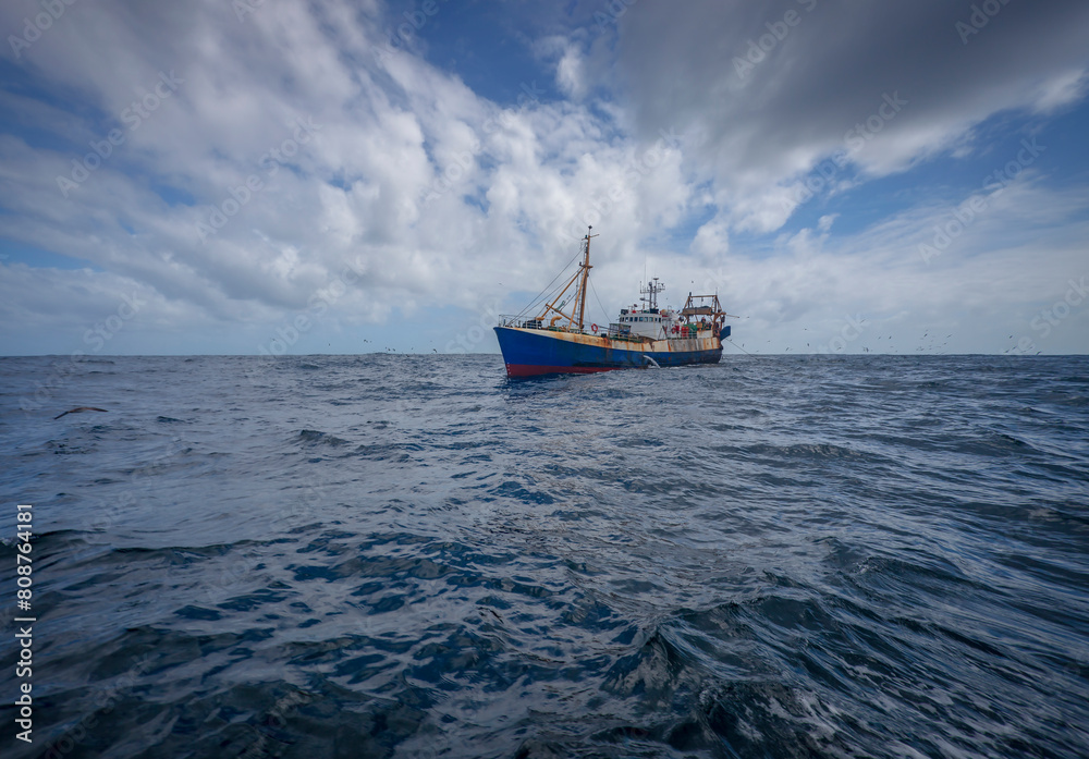 Average fishing trawler conducts trawling of fish in the waters of the ocean. Average fishing trawler conducts trawling of fish in the waters of the ocean.