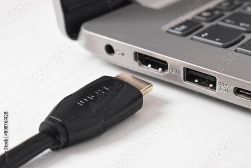 Man is connecting black HDMI cable into HDMI port of the modern laptop on white background