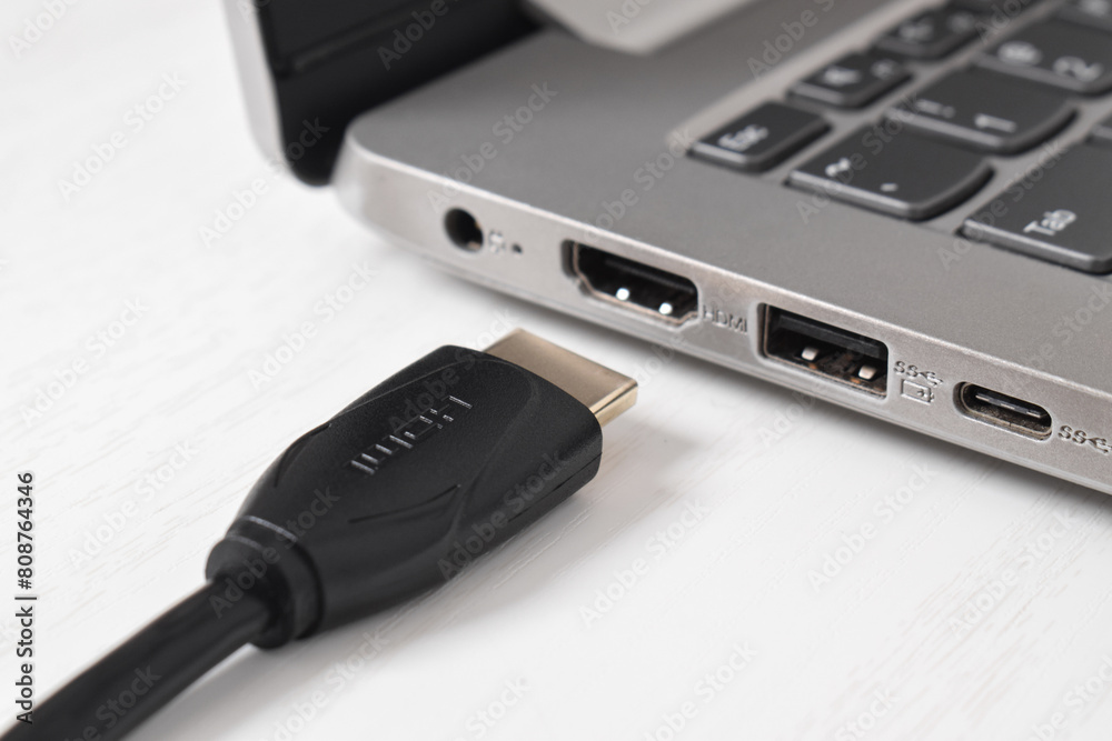 Man is connecting black HDMI cable into HDMI port of the modern laptop on white background Man is connecting black HDMI cable into HDMI port of the modern laptop on white background