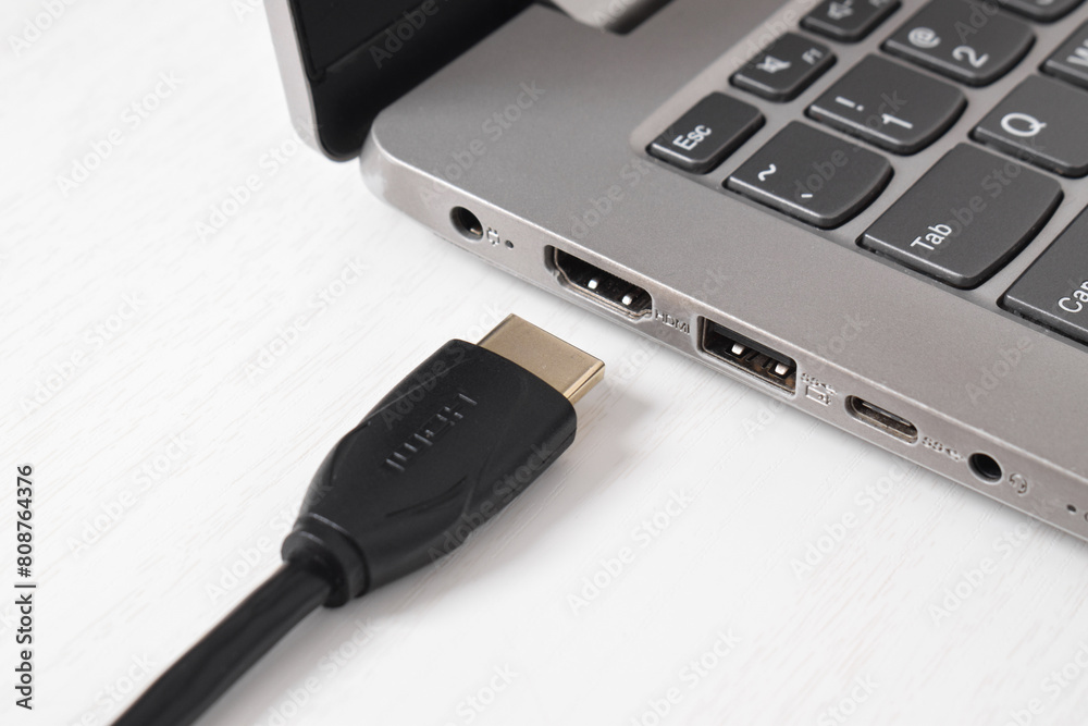 Man is connecting black HDMI cable into HDMI port of the modern laptop on white background Man is connecting black HDMI cable into HDMI port of the modern laptop on white background