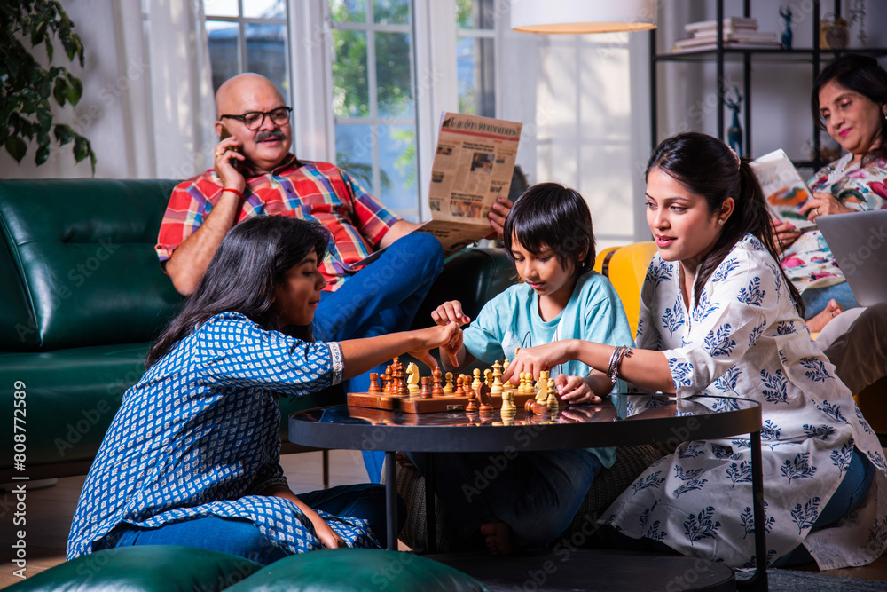 Φωτογραφία Indian asian multigenerational family playing chess in living room at home