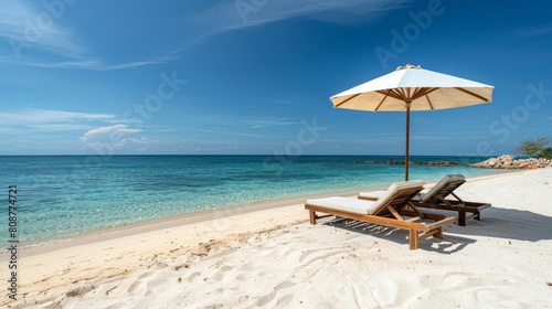 A panoramic view of the white sandy beach with two wooden sunbeds under an umbrella