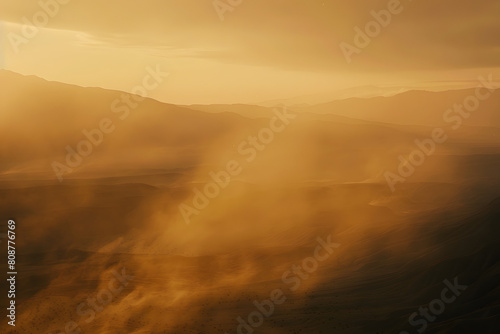Golden misty landscape illuminated by sunlight with mountains in the background