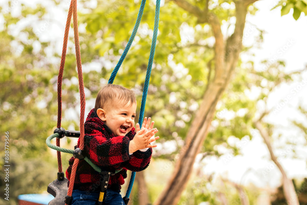 cute baby clapping on a swing in a playground